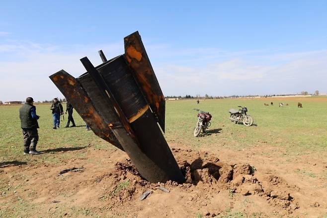 지난 4일 시리아 북동부 알카미슐리 남쪽 카즐라자 마을 주민들이 들판에 꽂힌 미사일을 살펴보고 있다. EPA 연합뉴스