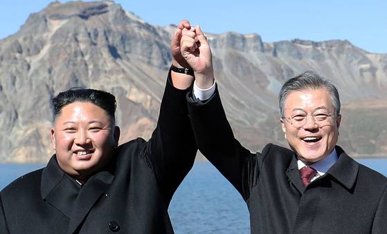North Korean leader Kim Jong-un, left, holds hands with then-South Korean President Moon Jae-in on Mount Paektu in North Korea on Sept. 20, 2018. [JOINT PRESS CORPS]
