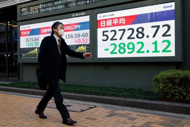 9일 일본 도쿄에 있는 증시 전광판 앞을 한 행인이 걸어가고 있다.[사진=EPA·연합뉴스]