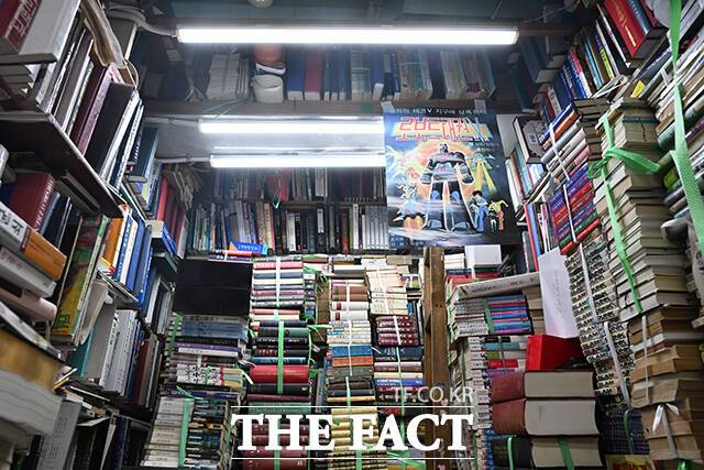 채 씨의 서점에 '로보트태권브이' 포스터와 함께 책들이 쌓여있다.