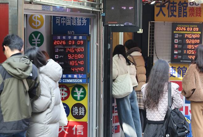 People wait in line at the currency exchange booth in Myeongdong, central Seoul, on March 9. [YONHAP]