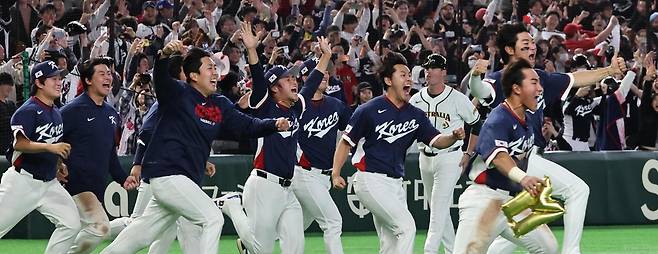 한국 야구 대표팀 선수들이 9일 일본 도쿄돔에서 열린 2026 월드베이스볼클래식(WBC) 조별리그 C조 최종 4차전에서 호주를 7-2로 꺾고 2라운드(8강) 진출에 성공한 뒤 환호하며 그라운드로 달려 나오고 있다. 한국이 WBC 2라운드에 진출한 건 2009년 대회 이후 17년 만이다. 2라운드가 열리는 미국 플로리다주 마이애미(Miami)를 상징하는 ‘M’자 모양 풍선을 든 선수는 이날 9회초 희생플라이로 한국에 마이애미행 티켓을 안긴 안현민이다. 도쿄=뉴스1