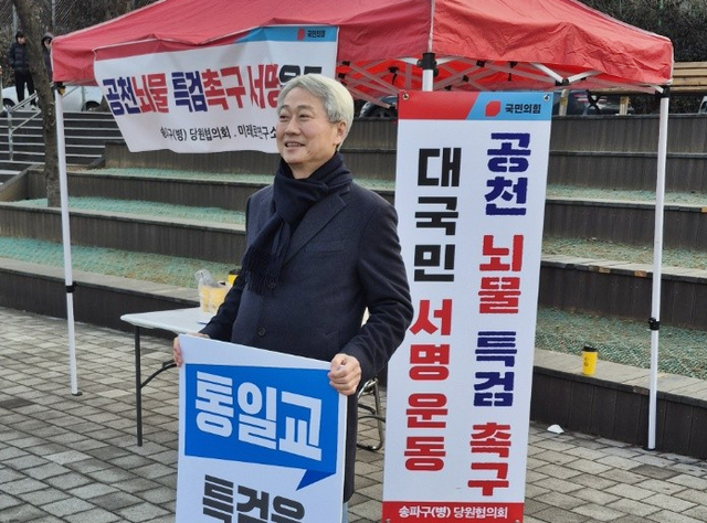 국민의힘 서울 송파병 당협위원장인 김근식 전 비전전략실장이 지난 2월 지역구에서 당협 명의로 통일교 공천뇌물 특검 촉구 대국민 서명운동을 주도하며 대형 팻말을 들고 서 있다.[김근식 경남대 교수 페이스북 사진]