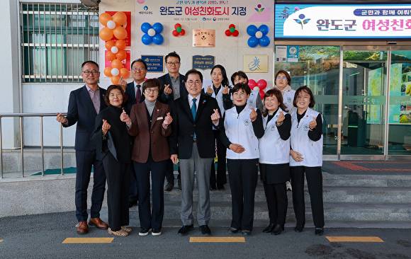 여성 친화 도시 현판 앞에서 군 관계자 및 여성 단체가 손하트를 하고 있다.  [사진=완도군청]