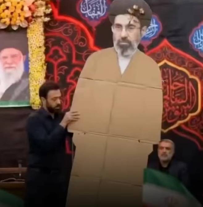 이란 혁명수비대(IRGC)의 최고 지도자 모즈타바 하메네이가 테헤란에서 열린 최고 지도자 임명식에 불참한 것으로 알려졌다. 이날 현장에는 실물 크기 골판지 패널과 액자에 담긴 초상화만 전시된 것으로 전해졌다. 사진=온라인 커뮤니티