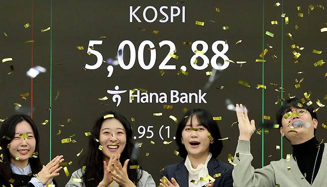 코스피가 22일 미국의 유럽에 대한 관세 철회 소식에 상승해 사상 처음 5,000선을 돌파했다. 사진은 코스피가 장중 5,000을 넘어선 가운데 22일 오전 서울 중구 하나은행 딜링룸에서 딜러들이 기뻐하고 있는 모습. /연합뉴스