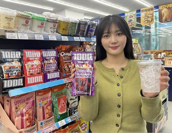 GS25에서 모델이 1000원 아이스커피 파우치 상품과 얼음컵을 들고 포즈를 취하고 있다. (사진=GS리테일)