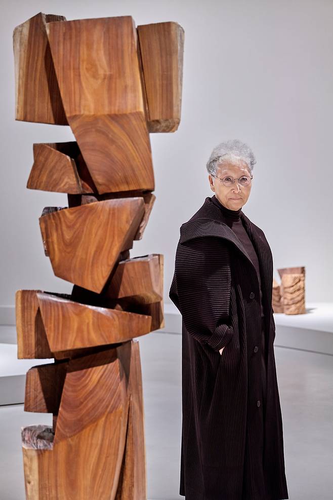 전시장에서 ‘합이합일 분이분일 1987-88’(1987) 옆에 서 있는 김윤신. 아르헨티나 이주 4년째에 제작한 작품으로 뉴욕 구겐하임미술관이 소장하고 있다. 높이 181.3㎝. 안정감 있는 밑동 위로 다양한 형태의 돌기들이 서로 다른 각도와 밀도로 맞물리며 올라가 마치 조각의 뼈대를 이루는 듯한 구성이다. /호암미술관