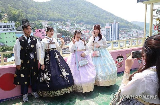 지난해 12월 부산 감천문화마을을 찾은 외국인 관광객들이 한복을 입고 전망대에서 기념촬영하고 있다. 연합뉴스 제공