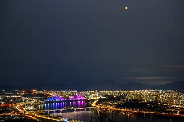 아차산 정상인 제3보루에서 내려다본 구리암사대교·고덕토평대교·강동대교 일대가 야간 경관 조명과 차량 불빛 등으로 화려한 풍경을 펼쳐 놓고 있다. 하늘에는 36년 만에 정월대보름과 개기월식이 맞물려 붉게 보이는 '블러드문'이 떠 있다.