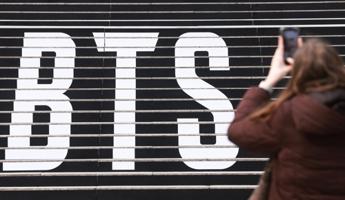 지난 11일 서울 종로구 세종문화회관 계단에서 외국인 팬이 ‘완전체’로 돌아오는 그룹 방탄소년단(BTS) 공연 홍보물을 촬영하고 있다. [연합뉴스]