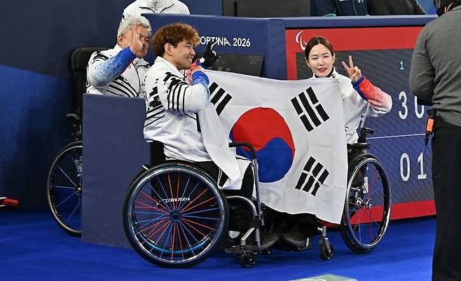 [서울=뉴시스] 사진공동취재단 = 한국 휠체어컬링 믹스더블 국가대표 백혜진-이용석 조가 11일(현지 시간) 이탈리아 코르티나담페초의 코르티나 올림픽 컬링 스타디움에서 열린 2026 밀라노·코르티나담페초 동계패럴림픽 휠체어컬링 믹스더블 결승에서 중국에 7-9로 져 은메달을 딴 후 태극기를 들고 있다. 2026.03.11 *재판매 및 DB 금지