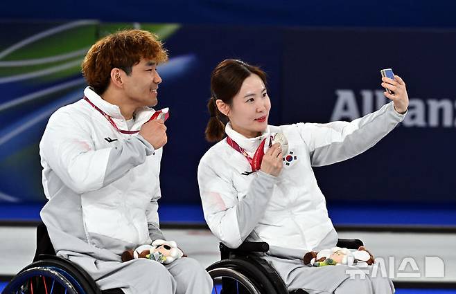 [코르티나담페초=뉴시스] 사진공동취재단 = 휠체어컬링 백혜진(오른쪽)과 이용석이 11일(현지 시간) 이탈리아 코르티나담페초 컬링 올림픽 스타디움에서 열린  2026 밀라노 코르티나 패럴림픽 휠체어컬링 믹스더블에서 은메달을 차지한 뒤 셀프카메라를 찍고 있다. 2026.03.12. photo@newsis.com