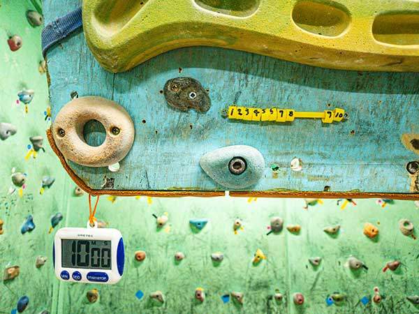 트레이닝 보드에는 훈련을 위한 타이머와 빨대로 손수 만든 숫자 막대기가 있다. 나무 홀드에 매달려 손가락 힘과 팔 근육을 기르는 훈련을 할 수 있다.