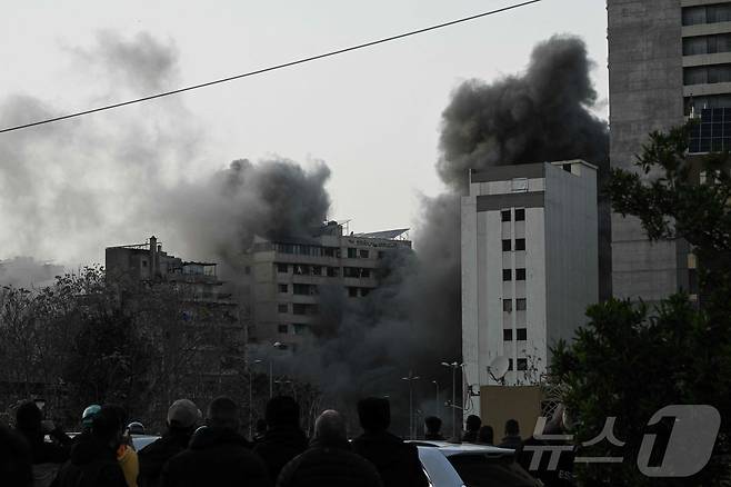 이스라엘 미사일 공습 이후 12일(현지시간) 레바논 베이루트 중심가 바슈라(Bashoura) 지역 상공으로 연기가 치솟는 모습을 시민들이 바라보고 있다. 2026.03.12ⓒ AFP=뉴스1