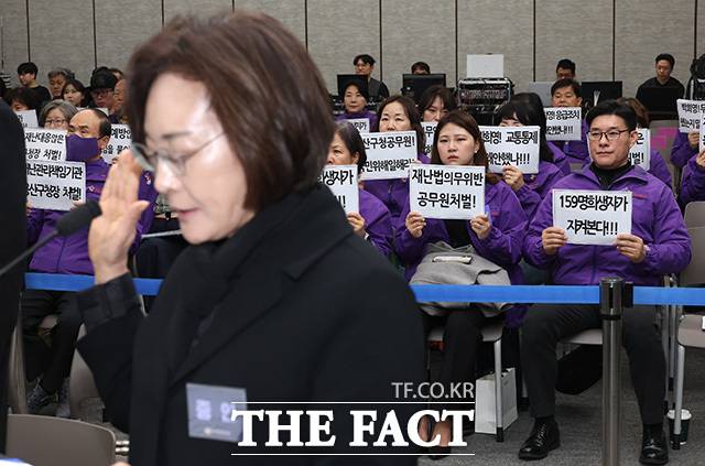 박희영 용산구청장이 13일 오전 서울 중구 은행회관에서 열린 '10·29 이태원 참사 진상규명 청문회'에 출석해 증인선서를 하는 가운데 유가족들이 책임자 처벌을 촉구하는 손팻말을 들고 있다. /송호영 기자