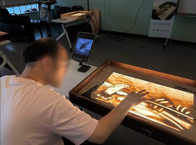 발달장애인 근로자가 생성한 AI 이미지를 바탕으로 샌드아트 작품을 제작하는 모습./사진=한국장애인고용공단 제공