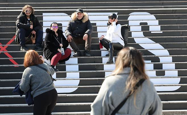 방탄소년단의 컴백 라이브 공연을 일주일여 앞둔 13일 서울 종로구 세종문화회관 계단에 마련된 방탄소년단 공연 홍보물 앞에서 외국인 관광객들이 기념촬영을 하고 있다.