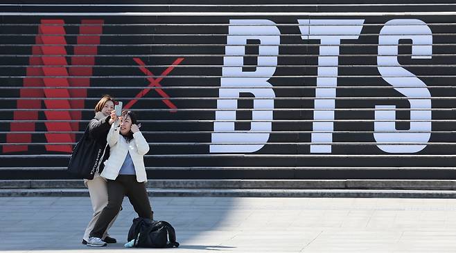 방탄소년단의 컴백 라이브 공연을 일주일여 앞둔 13일 서울 종로구 세종문화회관 계단에 마련된 방탄소년단 공연 홍보물 앞에서 외국인 관광객들이 기념촬영을 하고 있다.