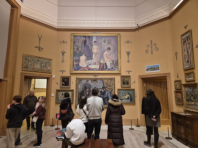 벽을 빽빽하게 채운 그림들은 ‘앙상블’ 방식으로 배치됐다. 정면 상단에 걸린 그림이 조르주 쇠라의 [모델들] ©김슬기