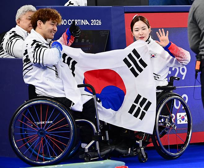 휠체어컬링 믹스더블 백혜전-이용석 조가 11일(현지시간) 이탈리아 코르티나 컬링 올림픽 스타디움에서 열린 2026 밀라노·코르티나 동계패럴림픽 휠체어컬링 믹스더블 결승에서 중국을 만나 연장 접전 끝에 아쉽게 패하며 은메달을 목에 걸었다. 경기 후 백혜진(오른쪽)과 이용석이 태극기를 들고 포즈를 취했다. 한국 휠체어컬링은 2010 밴쿠버 대회 이후 16년 만에 메달을 따냈다. 사진 | 대한장애인체육회