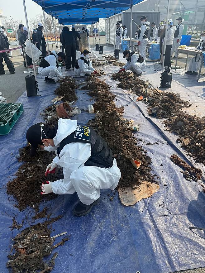 지난 12일 국토교통부와 항공철도사고조사위원회, 전남과학청 과학수사대 관계자들이 무안국제공항 공항소방대 뒤편에 보관된 여객기 잔해를 조사하고 있다. 연합뉴스