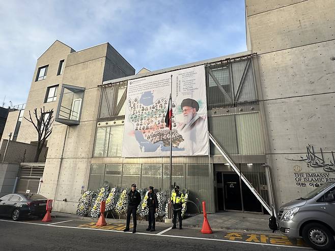 On the Iranian Embassy's outer wall hangs a large banner featuring a photograph of the late Supreme Leader Ali Khamenei — killed in U.S.-Israeli strikes — and the words: "When will the world hold war criminals accountable?" captured by the Korea JoongAng Daily on March 13. According to police officers on site, protests have become a frequent occurrence at the embassy in central Seoul. [SEO JI-EUN]