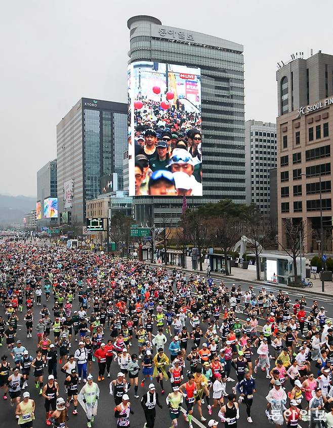 2026 서울마라톤 겸 제96회 동아마라톤에 출전한 마라토너들이 15일 오전 서울 광화문광장을 출발해 힘차게 달리고 있다. 동아미디어센터 외벽에 설치된 국내 최대 규모의 디지털 사이니지 ‘룩스(LUUX)’를 통해 선수들의 레이스 장면이 실시간으로 송출됐다. 송은석 기자 silverstone@donga.com