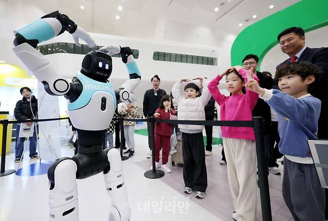 지난달 28일 서울 중구 동대문디자인플라자(DDP) 아트홀에서 열린 서울AI페스티벌 2026에서 아이들이 국내 최초로 일반에 공개되는 완전 자율형 민첩 로봇 ‘우치봇’과 머리 위로 하트 모양을 만들고 있다.ⓒ뉴시스