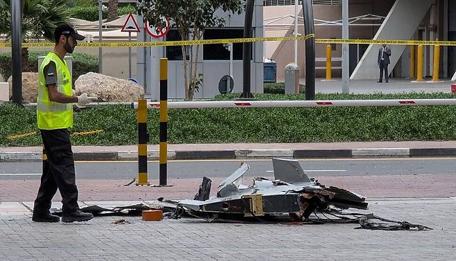 12일 아랍에미리트 두바이 도심에서 경찰관이 드론 잔해를 살펴보고 있다. 두바이는 이날 두 곳에 드론 잔해가 떨어졌다고 보고했다. AFP연합뉴스