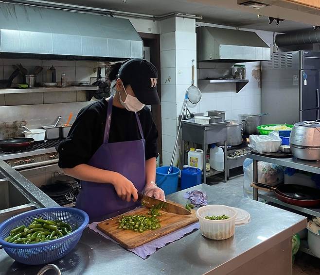 A Vietnamese student slices green peppers at a restaurant. [SON SUNG-BAE]