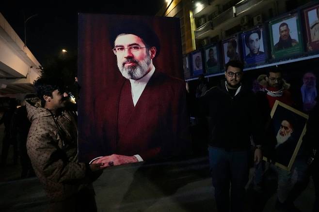 9일(현지시간) 이라크 바그다드에서 이라크인들이 이란 최고지도자로 선출된 모즈타바 하메네이를 지지하는 의미로 그의 초상화를 들고 있다. 모즈타바 하메네이는 미·이스라엘의 공습으로 사망한 아야톨라 알리 하메네이 전 최고지도자의 차남으로 8일 이란 최고지도자로 선출됐다./AP=뉴시스