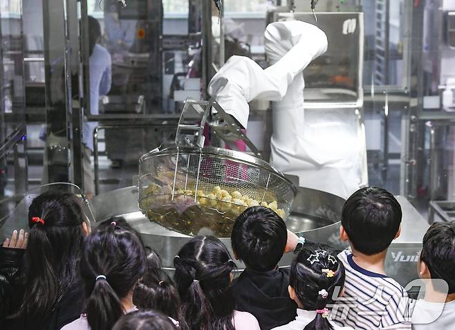 18일 경기 수원시 장안구 대평초등학교 내 위치한 거점형 학교급식 튀김 지원실에서 1학년 학생들이 튀김 조리 로봇이 직접 가동되는 현장을 보고 있다. (공동취재) 2026.3.18 ⓒ 뉴스1 김영운 기자