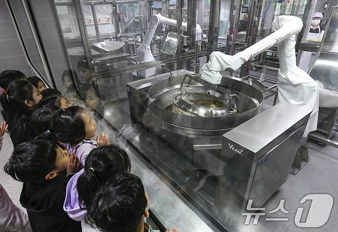 18일 경기 수원시 장안구 대평초등학교 내 위치한 거점형 학교급식 튀김 지원실에서 1학년 학생들이 튀김 조리 로봇이 직접 가동되는 현장을 보고 있다. (공동취재) 2026.3.18 ⓒ 뉴스1 김영운 기자