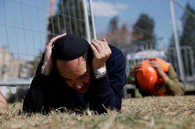 미국·이스라엘과 이란 간 전쟁이 발발한 지 사흘 째인 지난 2일 이스라엘 예루살렘 인근 베이트셰메시에서 이란의 탄도미사일 공격에 대한 경보음이 울리자 시민들이 땅에 엎드려 귀를 막은 채 몸을 보호하고 있다. /로이터 연합뉴스