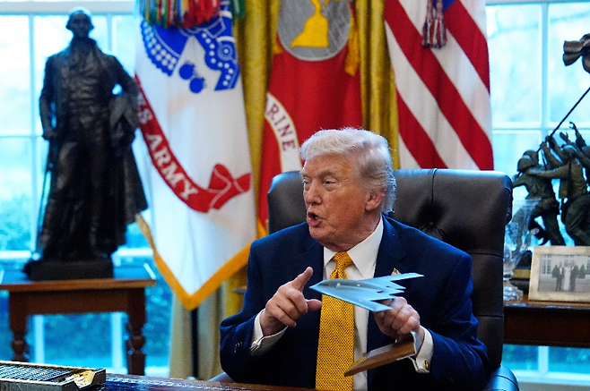 도널드 트럼프 미국 대통령이 16일(현지 시간) 백악관 집무실에서 가진 행정명령 서명식에서 미 공군의 스텔스 폭격기로 이번 이란 공격 때도 투입된 B-2 스피릿 모형을 들고 있다. 워싱턴=AP 뉴시스