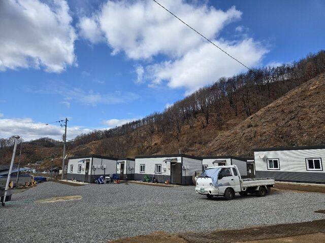 지난 3일 방문한 경북 안동시 임동면 일대의 임시주택 단지. 임시주택 뒤로 까맣게 그을린 산의 모습이 보인다. 마을 곳곳에 산불특별법 피해자 지원 신청을 안내하는 내용의 플래카드가 걸려 있다. 안동=김지훈 기자