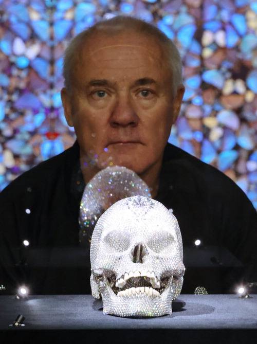 데이미언 허스트가 18일 국립현대미술관에서 열린 개인전에 전시된 '신의 사랑을 위하여' 작품과 함께 포즈를 취하고 있다.  연합뉴스