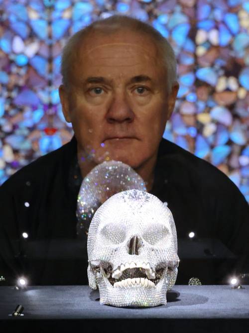 영국 작가 데이미언 허스트가 18일 서울 종로구 국립현대미술관에서 열린 ‘진실은 없어 그러나 모든 것은 가능하지’ 개인전에 전시된 ‘신의 사랑을 위하여’ 작품과 함께 포즈를 취하고 있다. <연합뉴스>