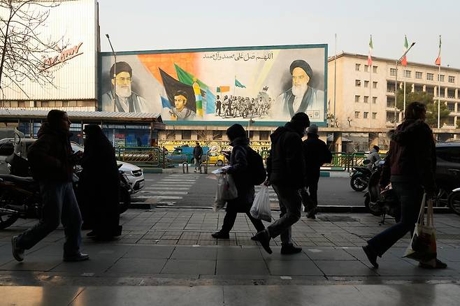 이란 테헤란의 거리에서 시민들이 아야톨라 알리 하메네이 벽화 앞을 지나고 있다.[AP]