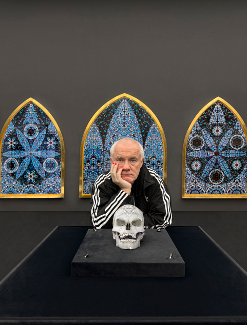 데이미언 허스트가 실제 인간의 해골을 백금으로 주조하고 8601개의 다이아몬드로 장식한 작품 ‘신의 사랑을 위하여’ 뒤에서 턱을 괴고 있다. 데이미언 허스트 사이언스 유한회사 제공