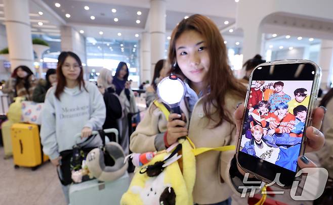 19일 인천국제공항에서 BTS 팬클럽 ‘아미’인 중국인 클로이(20)가 입국하며 아미밤(방탄소년단 공식 응원봉)을 들어 보이고 있다. 오는 21일 서울 광화문광장에서 열리는 BTS 컴백 공연을 관람하기 위해 전 세계 ‘아미’(BTS 팬)들이 속속 한국을 찾고 있다. 2026.3.19 ⓒ 뉴스1 박지혜 기자
