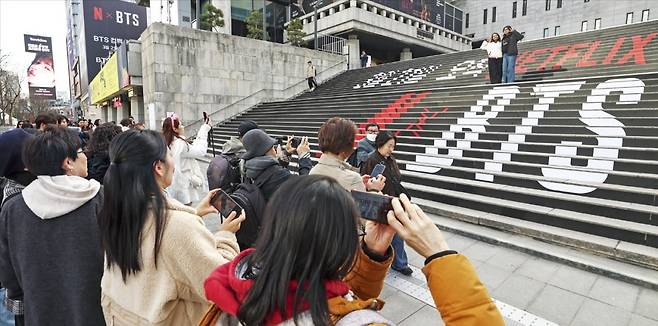 방탄소년단(BTS)의 컴백 공연을 이틀 앞둔 19일 서울 광화문광장에서 외국인 관광객이 BTS 관련 홍보물 앞에서 사진을 찍고 있다. 사진=임형택 기자