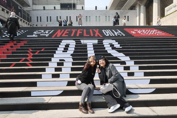 방탄소년단(BTS)의 서울 광화문광장 컴백 공연을 앞둔 17일 서울 종로구 세종문화회관 계단에서 외국인관광객이 BTS 컴백 공연 관련 래핑 광고를 배경으로 기념촬영을 하고 있다. 사진=임준선(이오이미지)