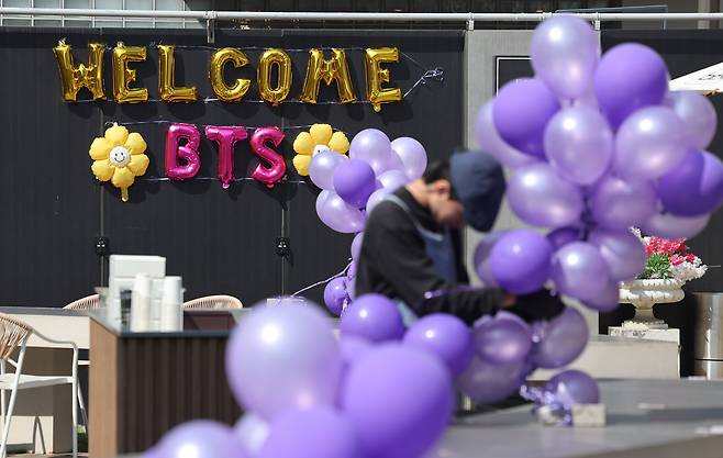 BTS 컴백 공연이 열리는 21일 서울 종로구 광화문광장 인근 매장에서 직원이 보라색 풍선과 리본으로 매장을 장식하며 아미(BTS 팬덤)들을 맞을 준비를 하고 있다./뉴스1