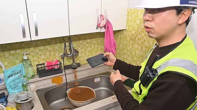 지난 20일 광주 광산구 평동 평지경로당 재능기부에 나선 ㈜KB배관홈닥터 관계자가 수도 배관을 통해 수도꼭지에서 쏟아지고 있는 시커먼 녹물에 대해 주민들에게 설명하고 있다. /조영권 기자