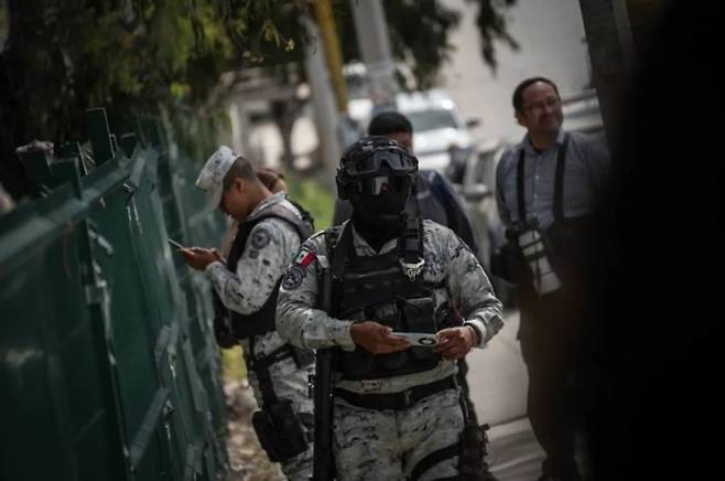 멕시코 경찰이 사건현장에서 휴대전화를 보고 있다. 콰르토오스쿠로 캡처