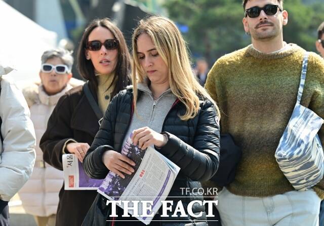 현대 대한민국의 정치·사회적 사건들이 축적된 공간을 콘서트 무대로 선택했다는 것 자체가 하나의 메시지였다. 사진은 공연 하루 전인 20일 오후 광화문 일대에서 외국인들이 BTS 관련 호외를 든 채 이동하고 있다. /이새롬 기자