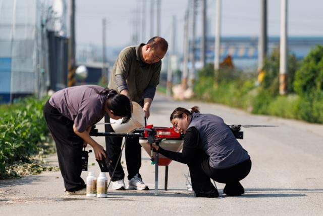 송태성(가운데)씨가 지난해 여름 비료를 뿌리기 위해 드론에 비료를 넣고 있다. 송씨 제공