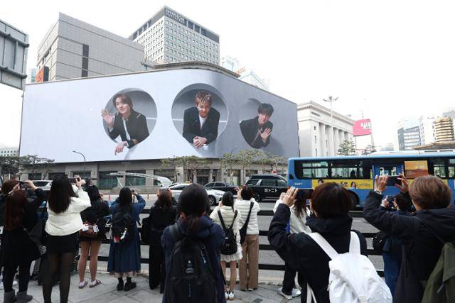 방탄소년단(BTS) 컴백 공연 다음 날인 22일 서울 중구 신세계백화점 전광판에서 송출되는 BTS 멤버들의 모습을 팬클럽 아미 회원들이 촬영하고 있다. 뉴스1